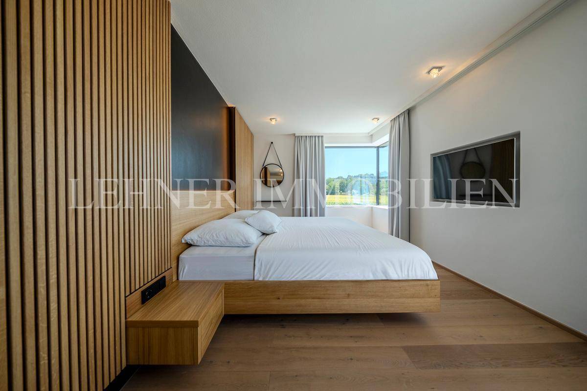 Modernes Schlafzimmer mit Holzbett, Akzentwand und großen Fenstern mit schöner Aussicht.