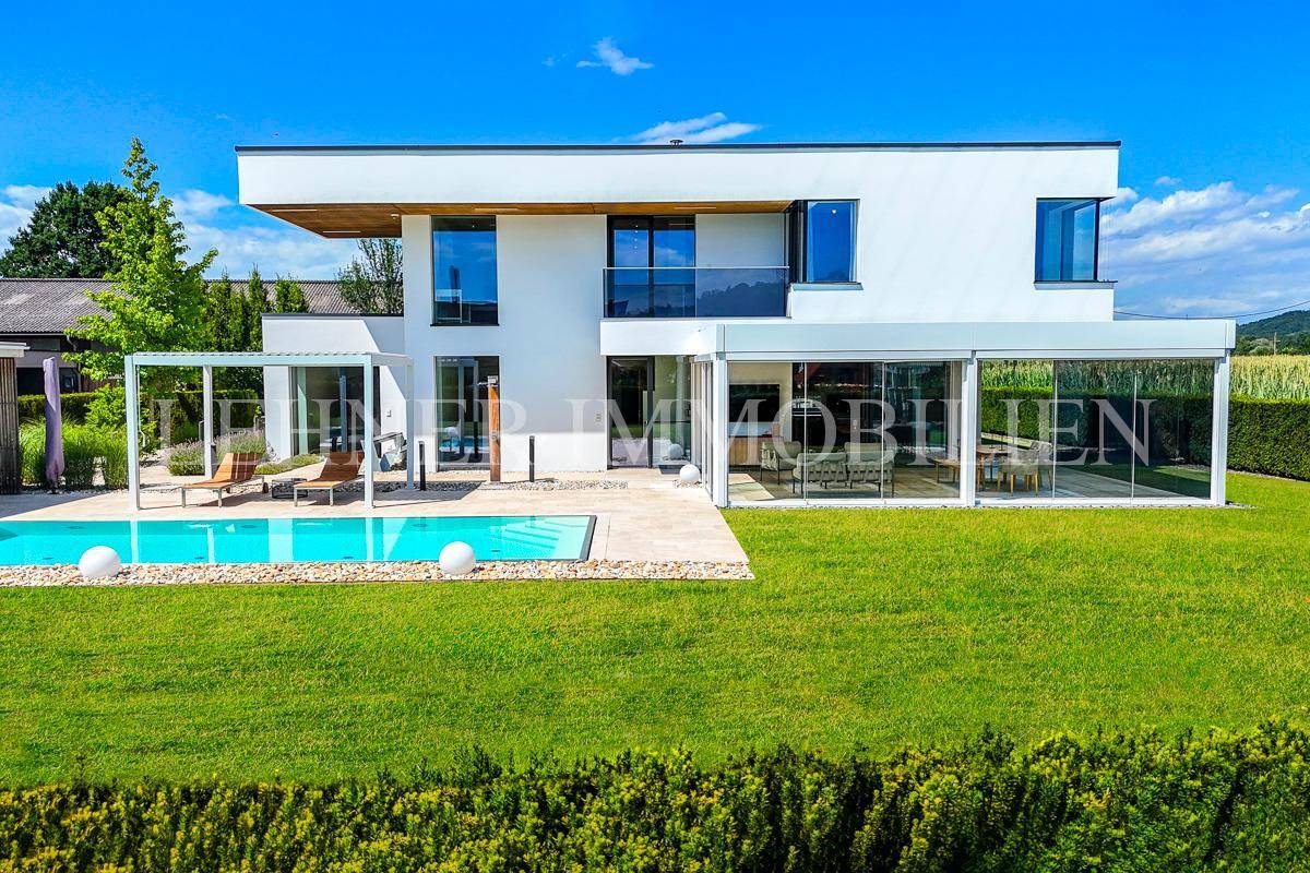Weitläufiger Gartenbereich mit modernem Pool und gepflegtem Rasen vor der zeitgenössischen Villa.
