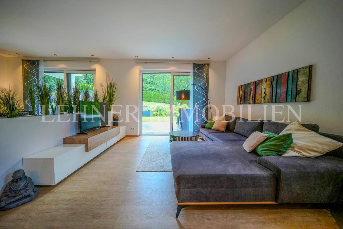 Heller Wohnbereich mit großem Ecksofa, modernem TV-Möbel und Zugang zur Terrasse.