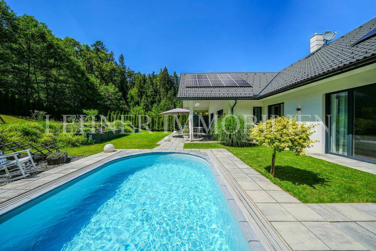 Außenansicht des Hauses mit Pool, gepflegtem Rasen und Solarpaneelen auf dem Dach.