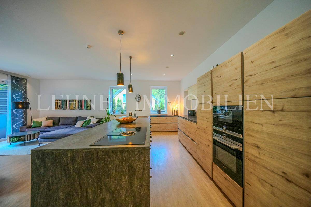 Moderne Holzküche mit integrierten Siemens-Geräten, Kochinsel und Blick ins Wohnzimmer.