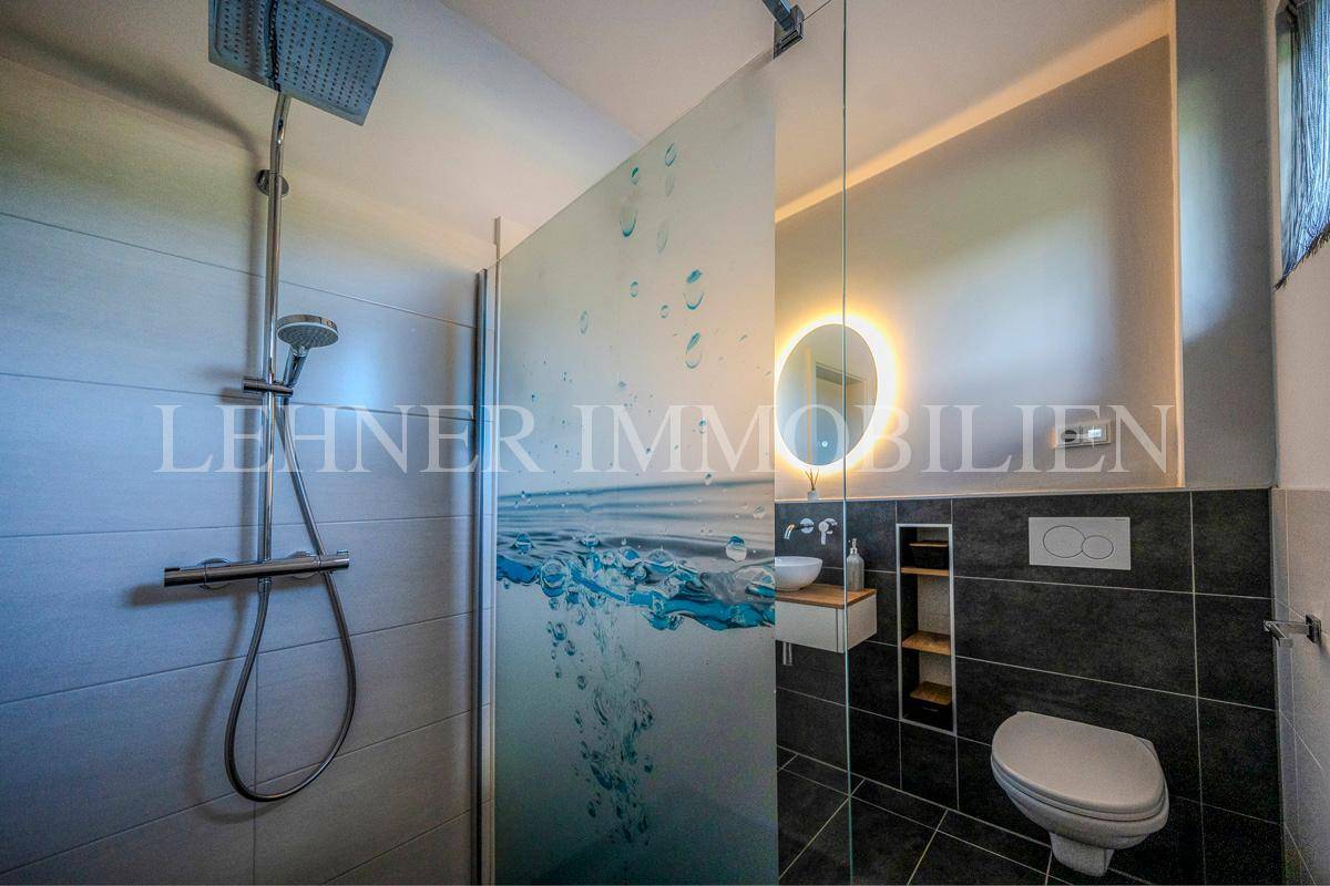Modernes Gäste-WC mit begehbarer Dusche, stilvollem Waschbecken und beleuchtetem Spiegel.