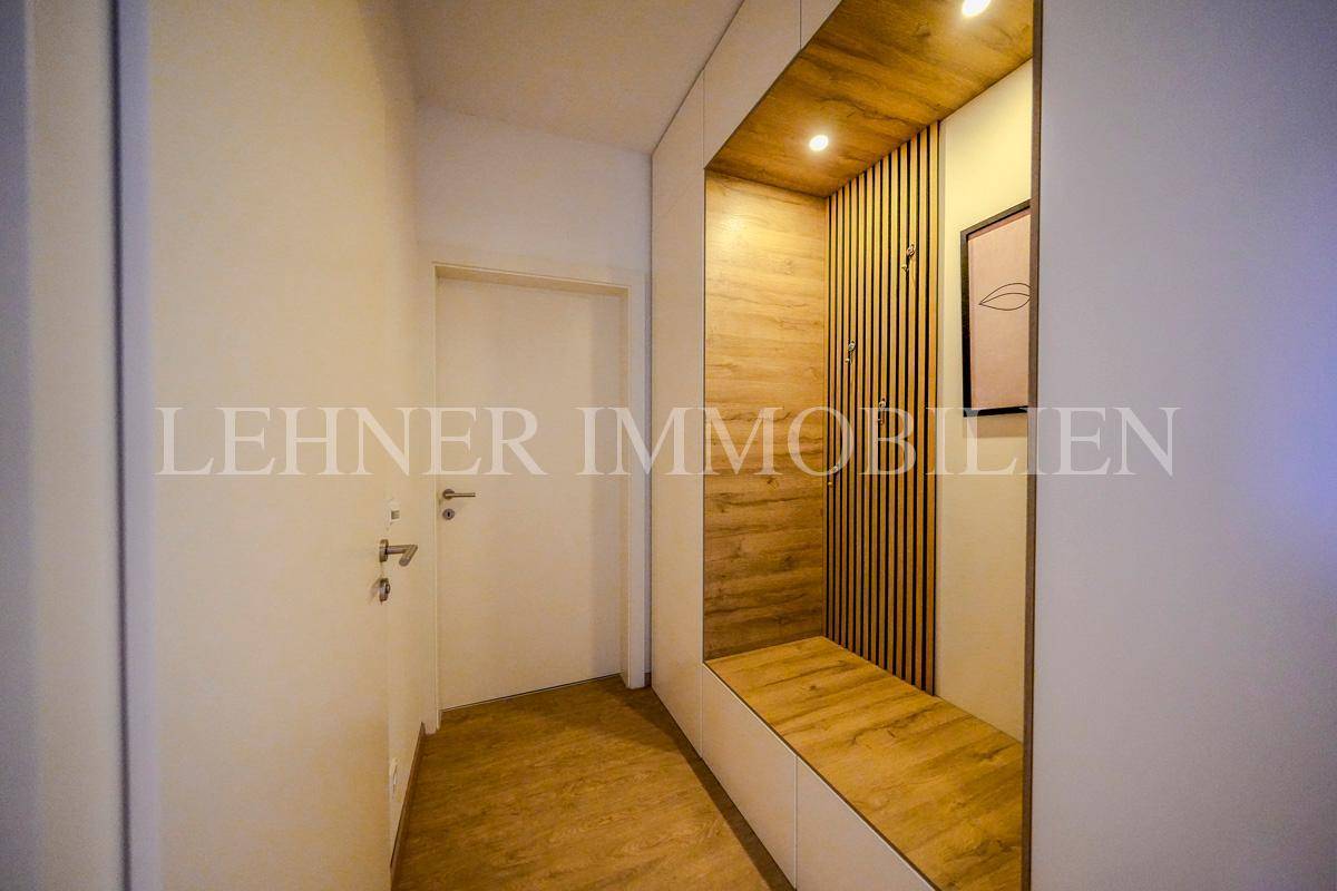 Heller Flur mit integrierter Garderobe und Sitzgelegenheit, modern gestaltet mit Holzlamellen.