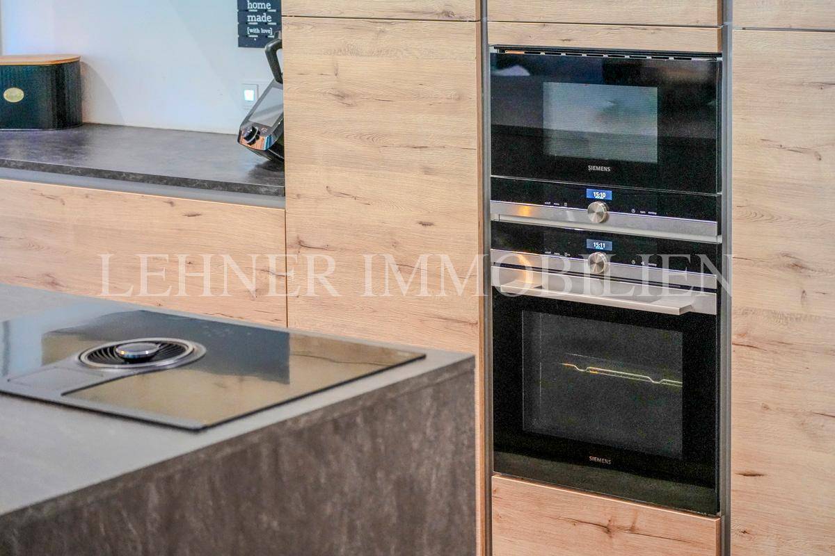 Integrierte Siemens-Einbaugeräte in der modernen Holzküche, inklusive Backofen und Mikrowelle.