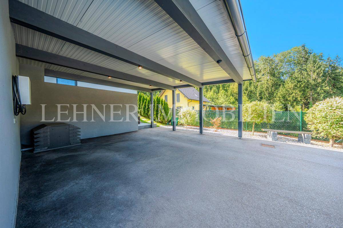 Weitläufiger Carport-Bereich mit Blick auf den gepflegten Garten und die grüne Umgebung.