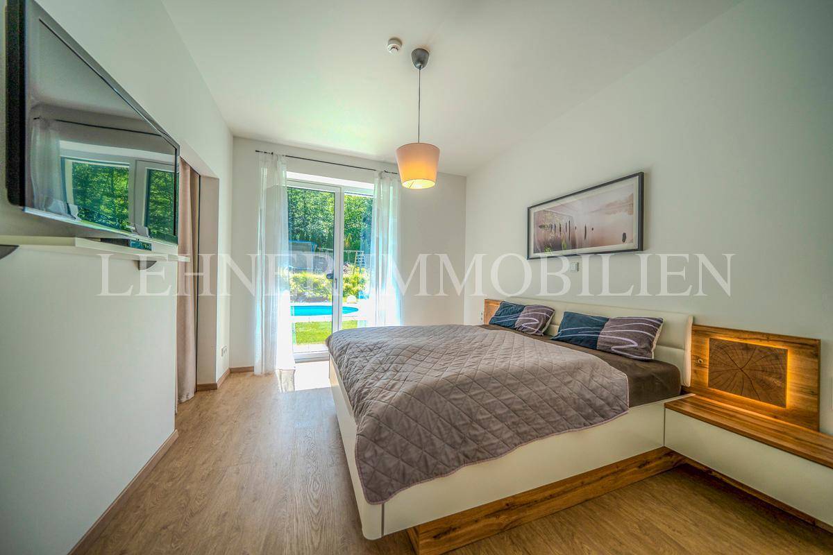 Helles Schlafzimmer mit Doppelbett, Holzelementen und direktem Zugang zum Außenbereich.