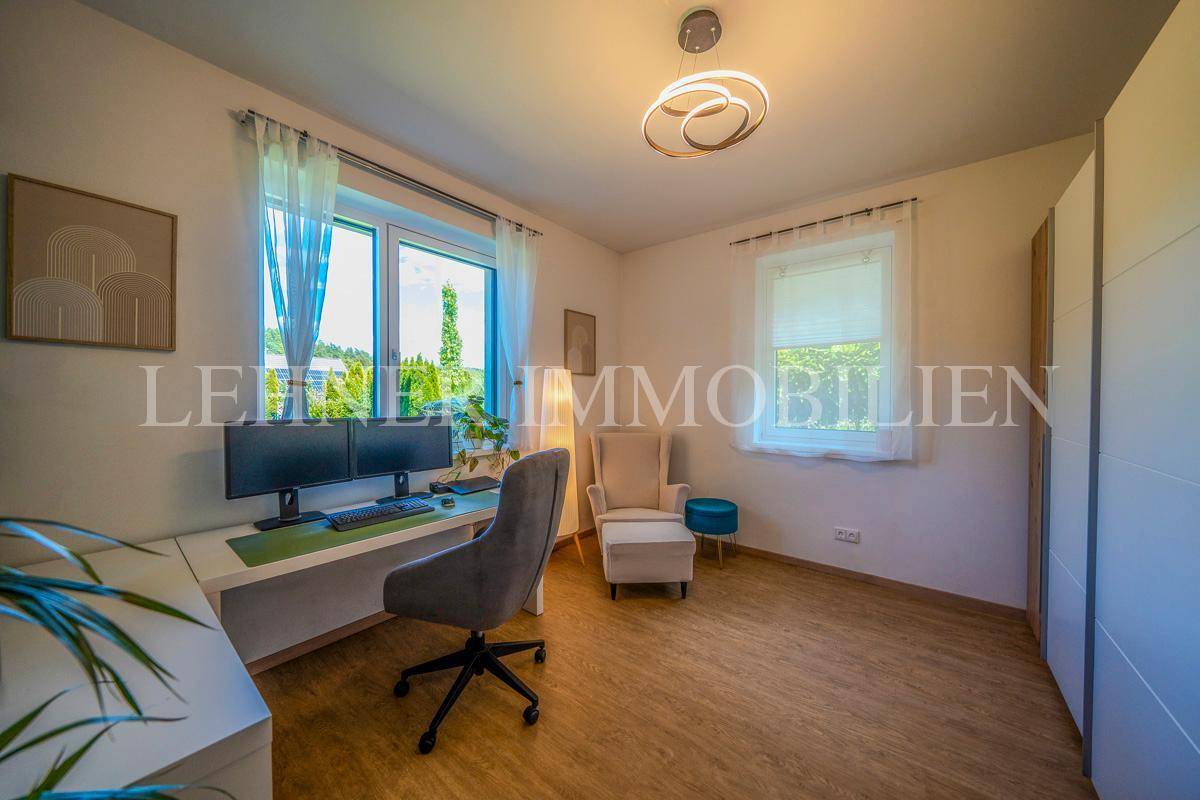 Helles Arbeitszimmer mit großem Schreibtisch, Bürostuhl und Blick ins Grüne.