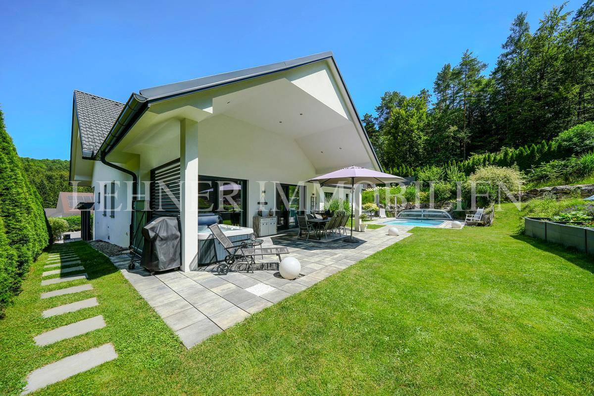 Seitliche Ansicht des Hauses mit überdachter Terrasse, Pool und weitläufigem Garten.