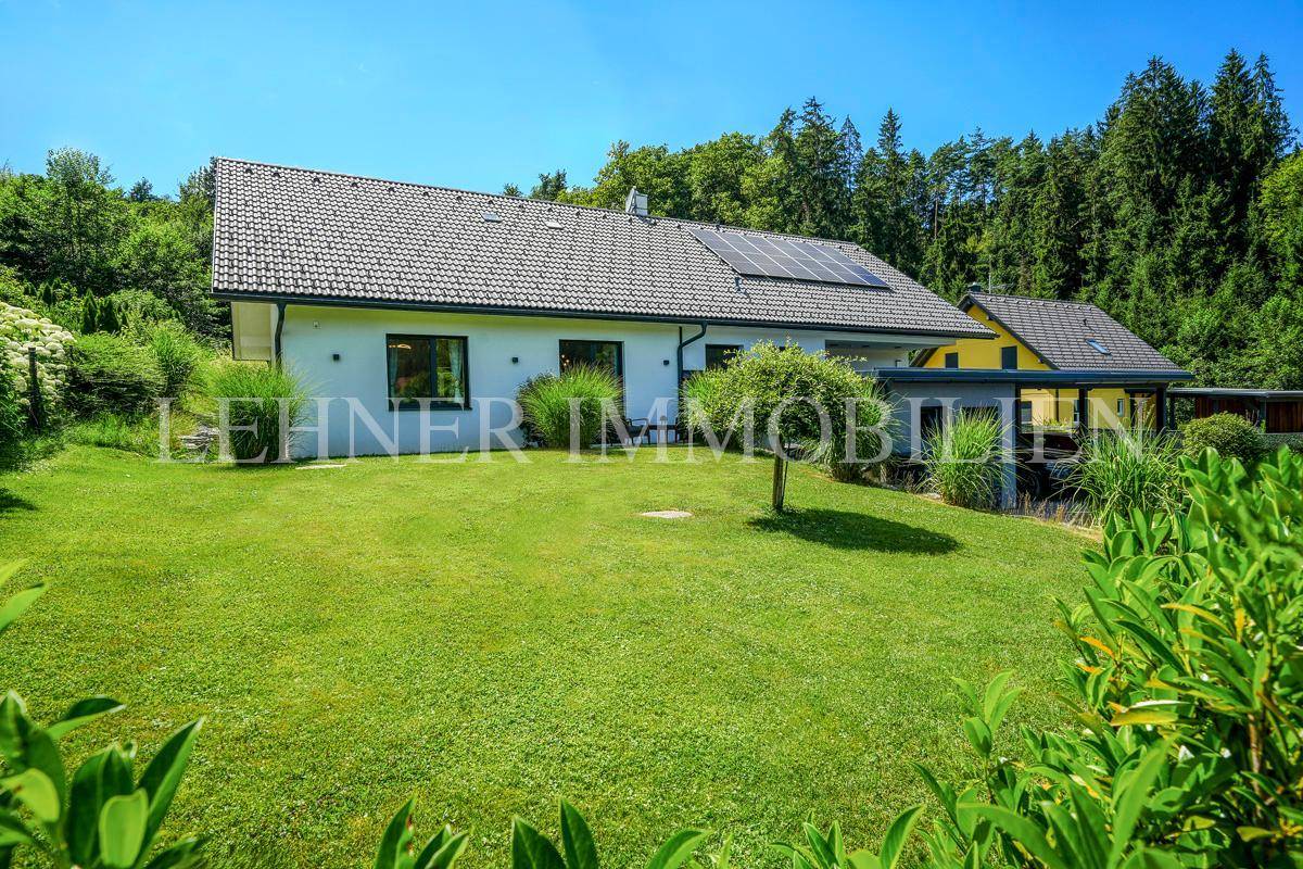 Gepflegter Garten mit weitläufiger Rasenfläche und Blick auf das moderne Einfamilienhaus.
