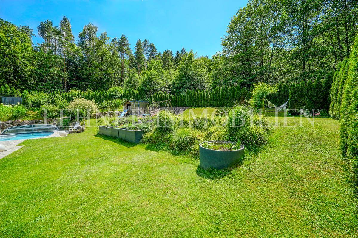 Weitläufiger Garten mit Rasenflächen, Hochbeeten und einer Hängematte im Grünen.