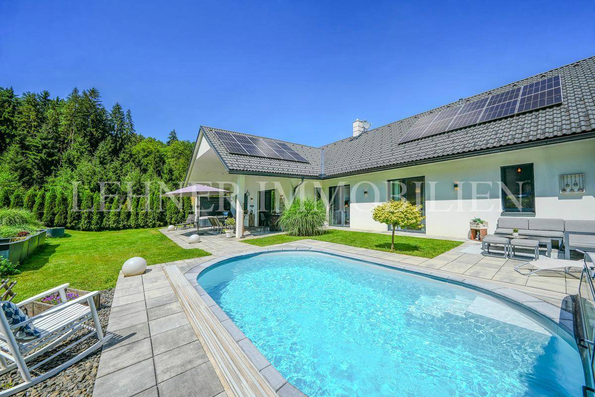 Weitläufiger Garten mit Pool, Terrasse und Blick auf die grüne Umgebung.