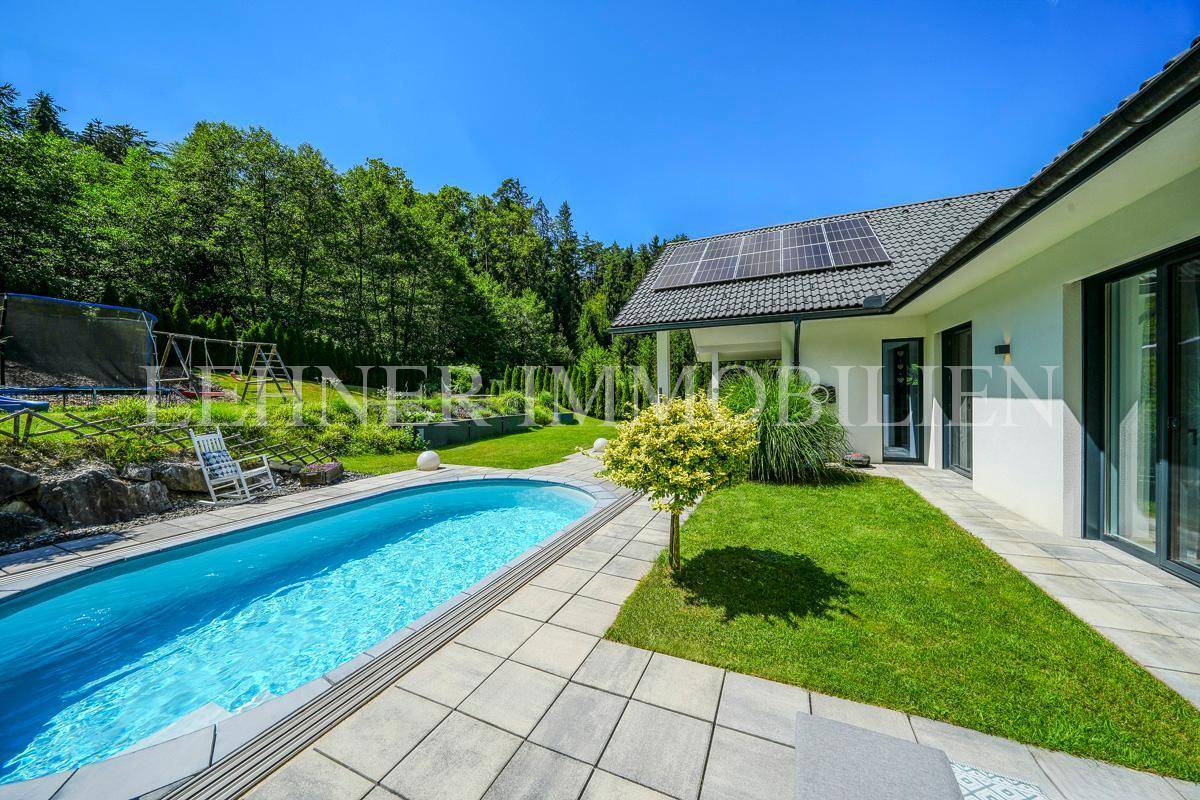 Sonniger Gartenbereich mit Pool, Rasen und Zugang zur Terrasse des Hauses.
