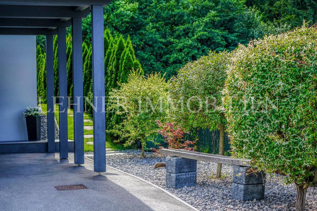 Gepflegter Gartenweg mit Zierbäumen und Kiesbeet neben dem Carport.