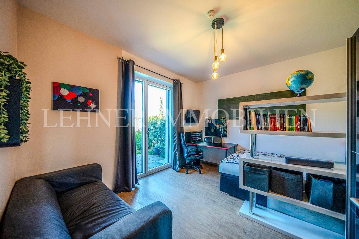 Jugendzimmer mit Schlafsofa, Schreibtisch und Zugang zur Terrasse.
