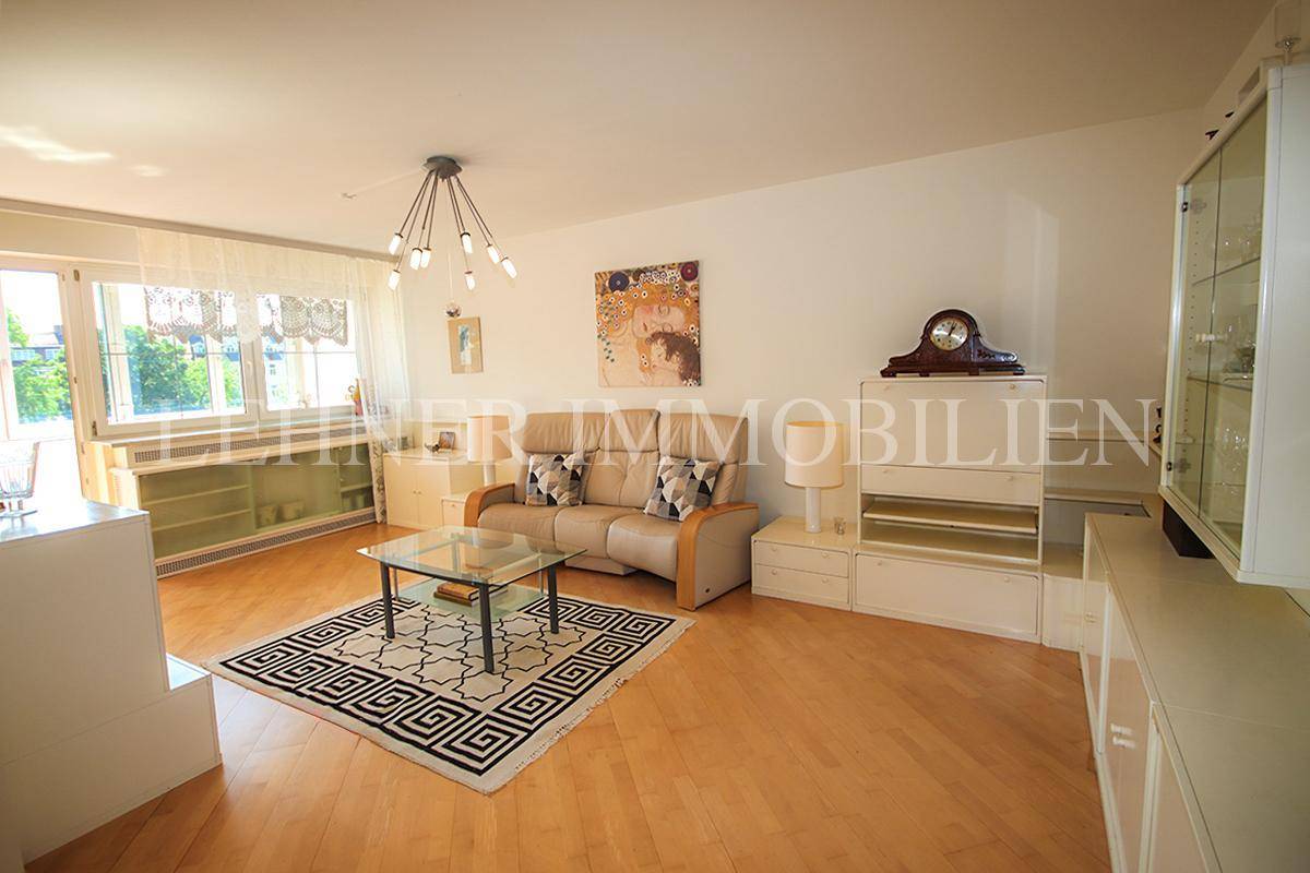 Gemütlicher Wohnbereich mit Sofa, Schrankwand und Blick auf die Fensterfront.