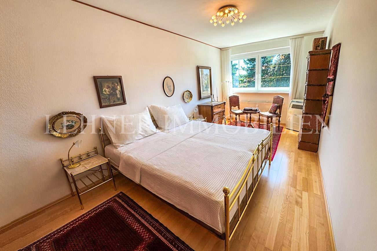 Gemütliches Schlafzimmer mit zwei Einzelbetten, Parkettboden und Fenster mit Grünblick.