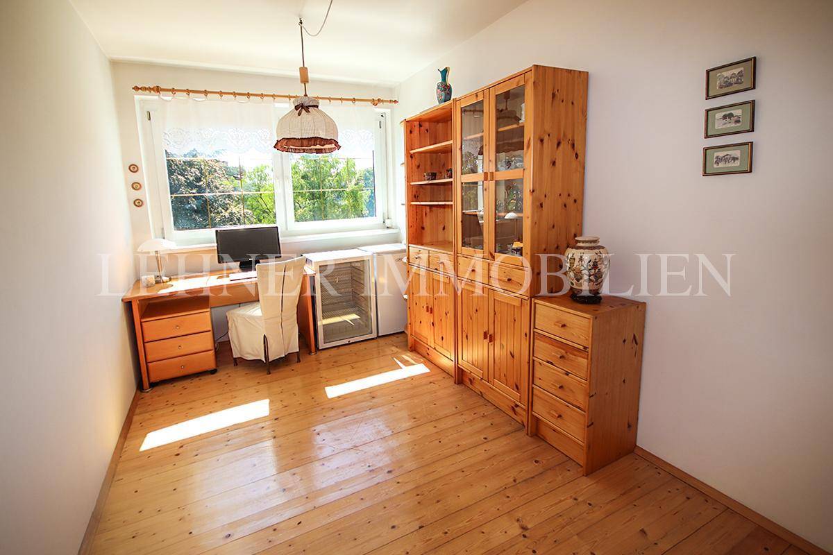 Helles Arbeitszimmer mit Kiefernholzmöbeln, Schreibtisch und großem Fenster.