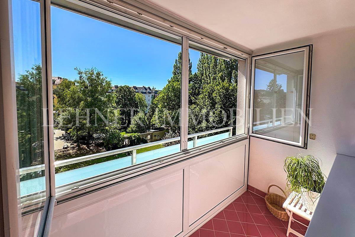 Verglaste Loggia mit rotem Fliesenboden und weitem Blick ins Grüne.