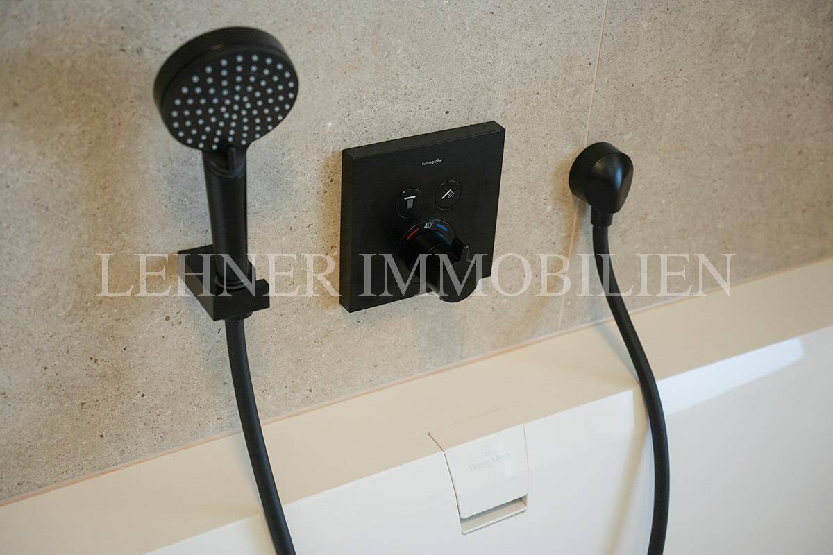 Nahaufnahme der modernen schwarzen Badewannenarmatur mit Handbrause und Temperaturregler.