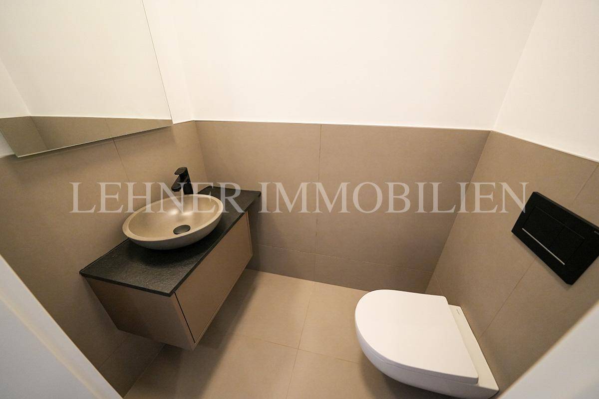 Modernes Gäste-WC mit Wand-WC, Aufsatzwaschbecken und beigefarbenen Fliesen.