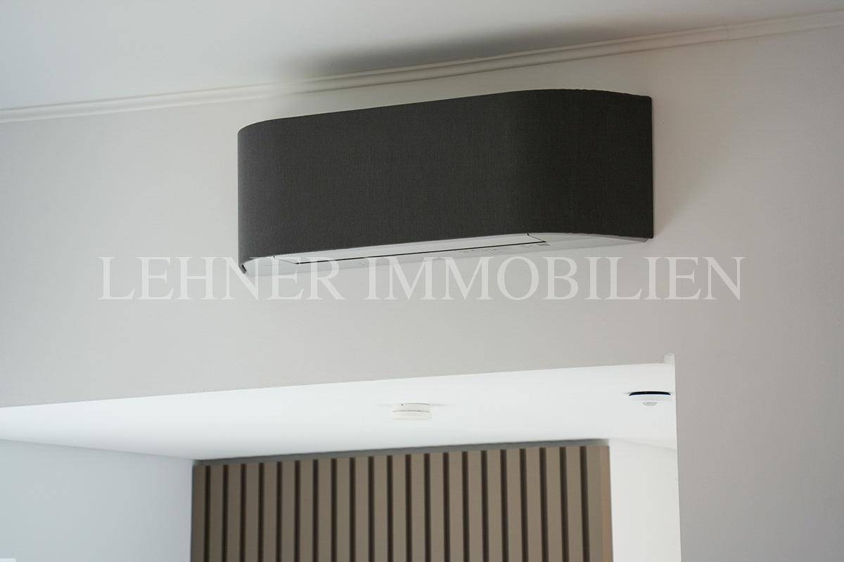 Detailaufnahme einer modernen Klimaanlage an einer weißen Wand.