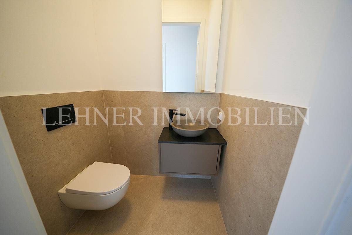 Modernes Gäste-WC mit Wand-WC, Aufsatzwaschbecken und stilvollen grauen Fliesen an den Wänden.