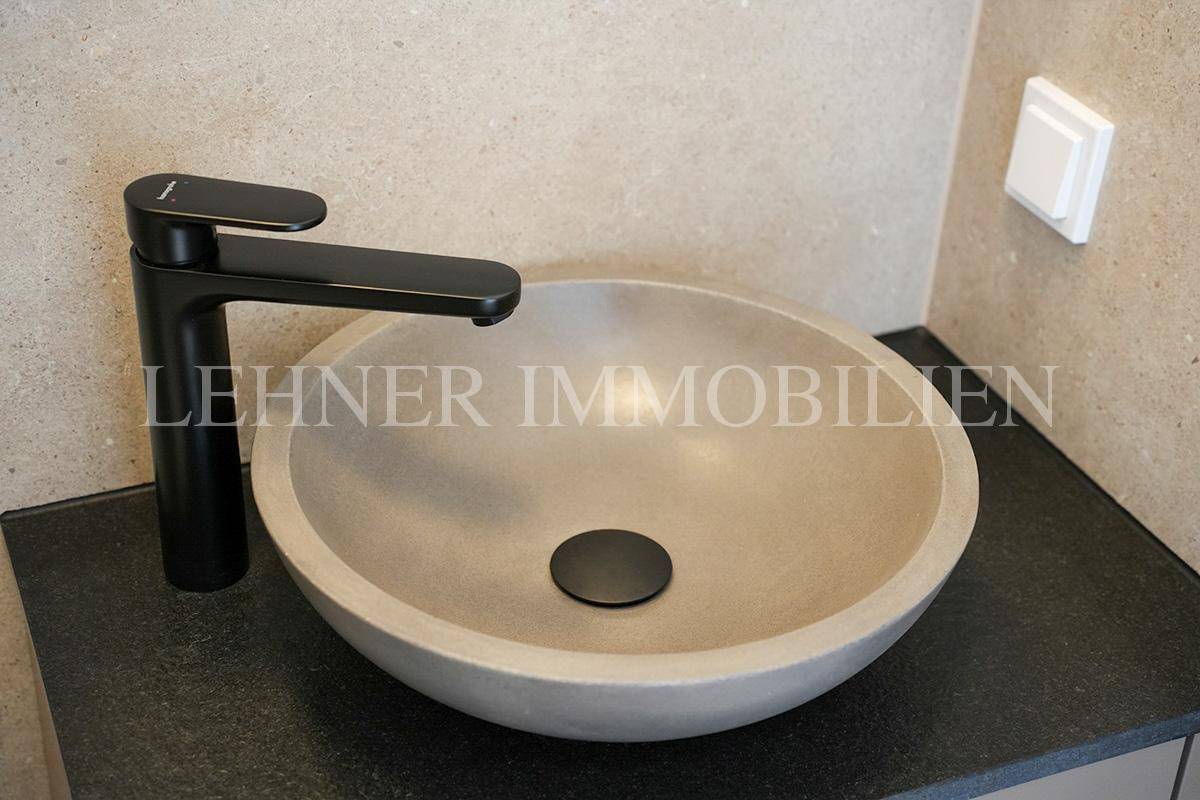 Nahaufnahme des modernen Aufsatzwaschbeckens mit schwarzer Armatur im stilvollen Gäste-WC.