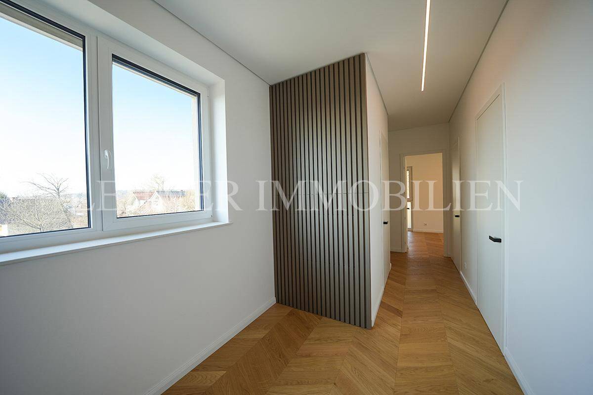 Heller Flur im Obergeschoss mit Fenster, Holzwandverkleidung und Parkettboden.