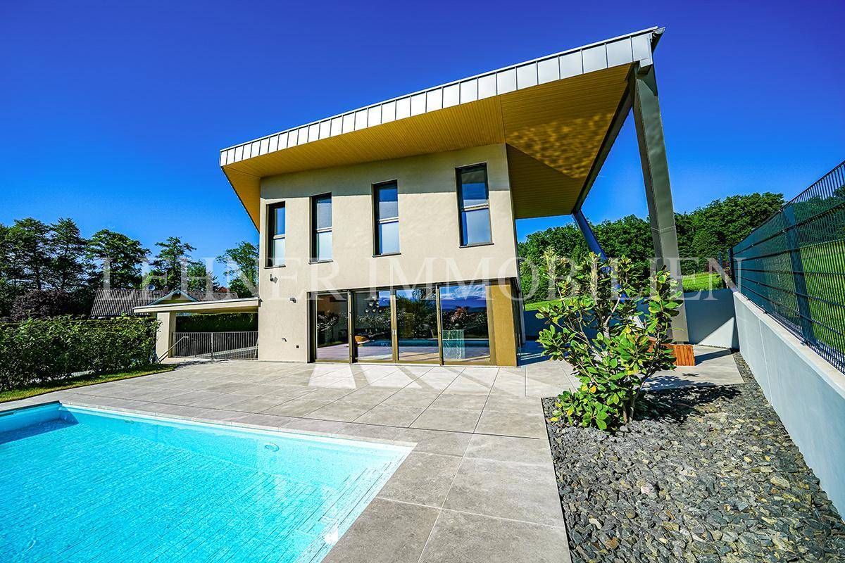 Zeitgenössisches Haus mit auffälligem Dachüberstand, Pool und Kiesbeet, eingebettet in grüne Umgebung.