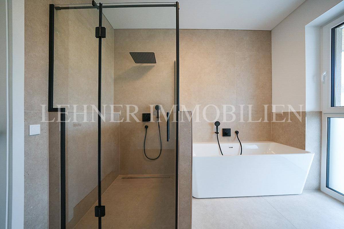 Modernes Badezimmer mit begehbarer Dusche, freistehender Badewanne und großen Fenstern für viel Licht.