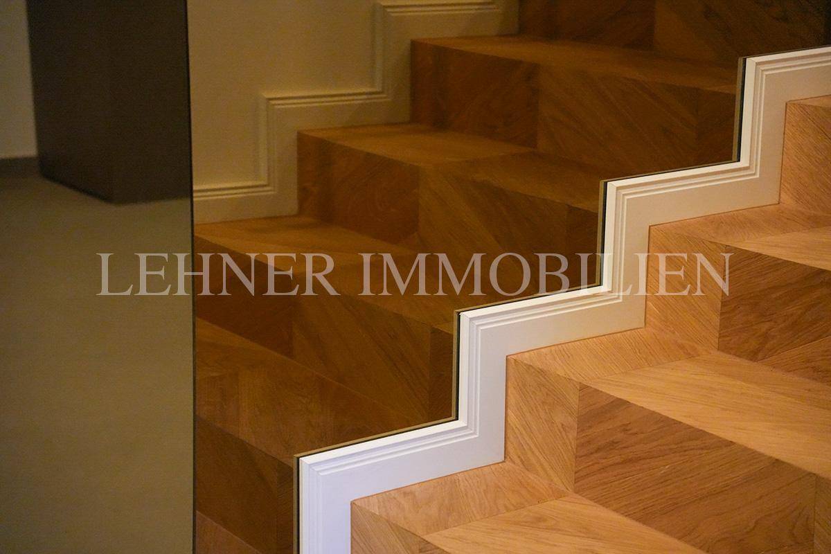 Detailansicht der Holztreppe mit Fischgrätmuster und weißer Sockelleiste.