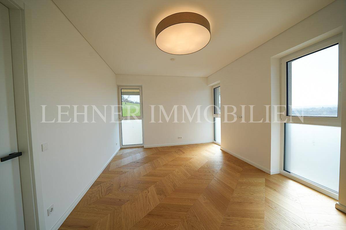 Helles Zimmer mit modernem Fischgrätparkett und großen Fenstern, ideal als Schlaf- oder Arbeitszimmer.