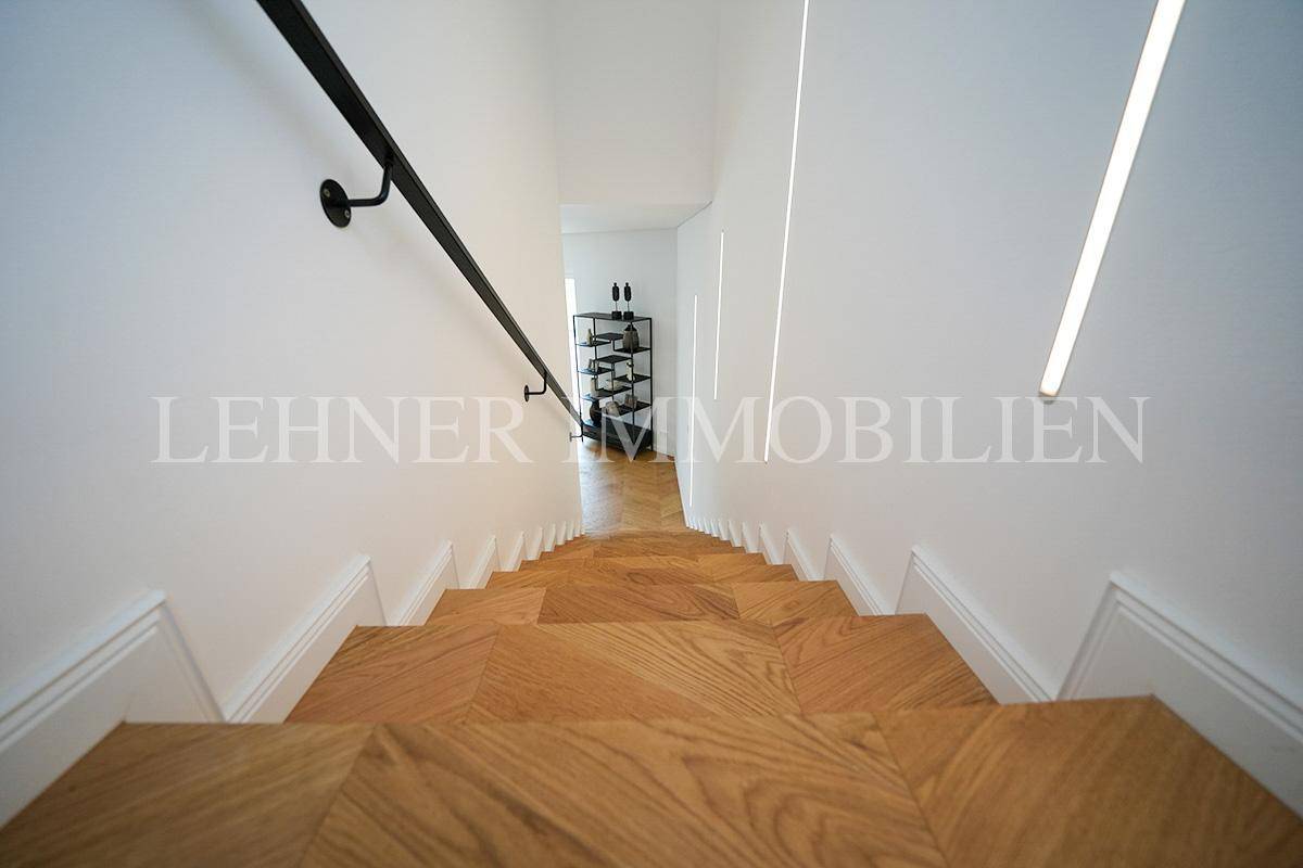 Blick von oben auf die Holztreppe mit modernem Geländer und indirekter Beleuchtung.