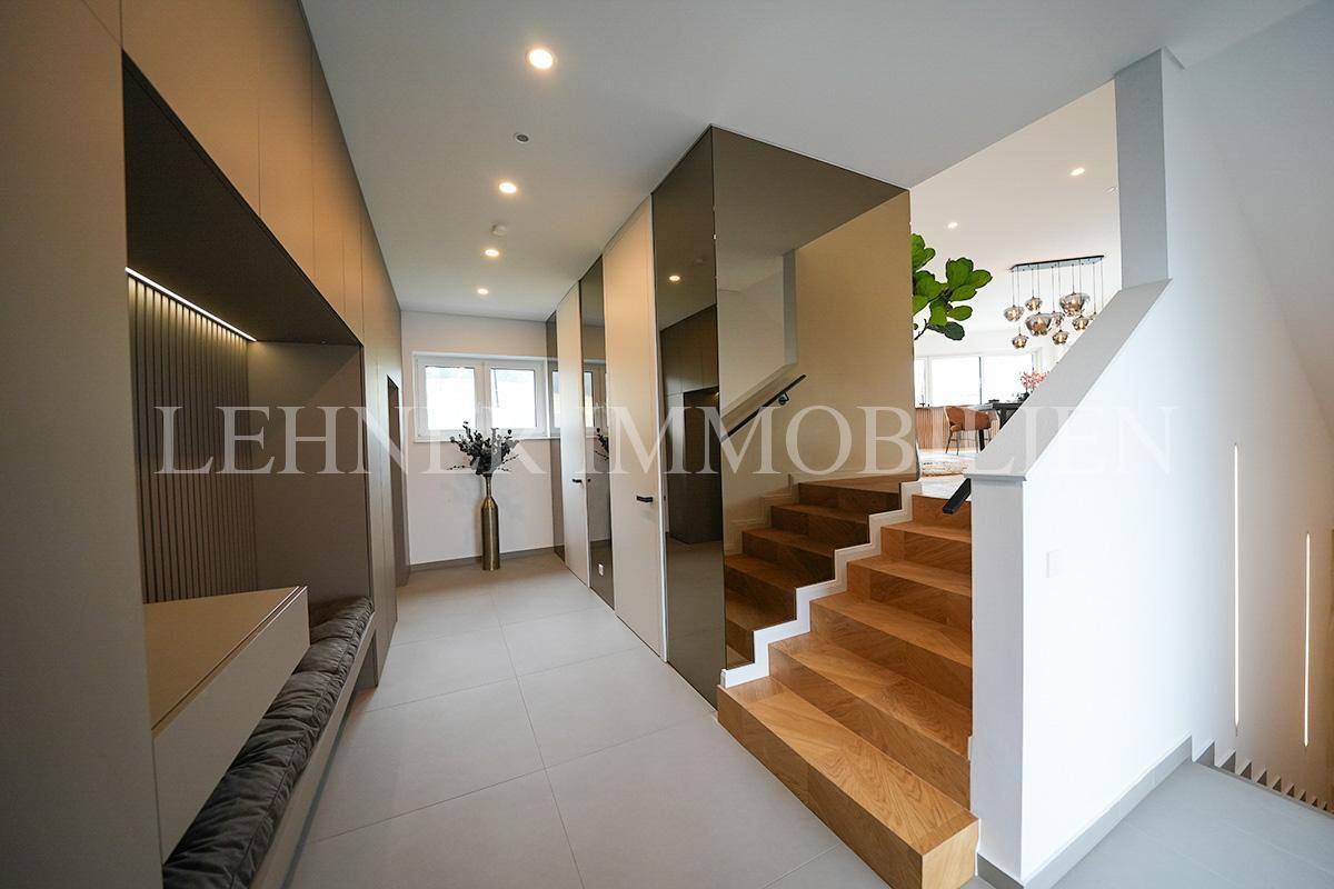 Geräumiger Flur mit moderner Holztreppe, Einbauschränken und viel Tageslicht.