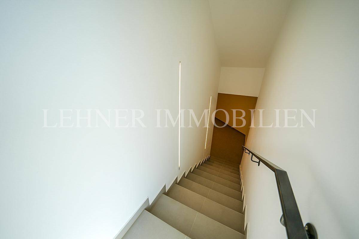 Treppenhaus mit minimalistischem Design, indirekter Beleuchtung und schlichtem Geländer.