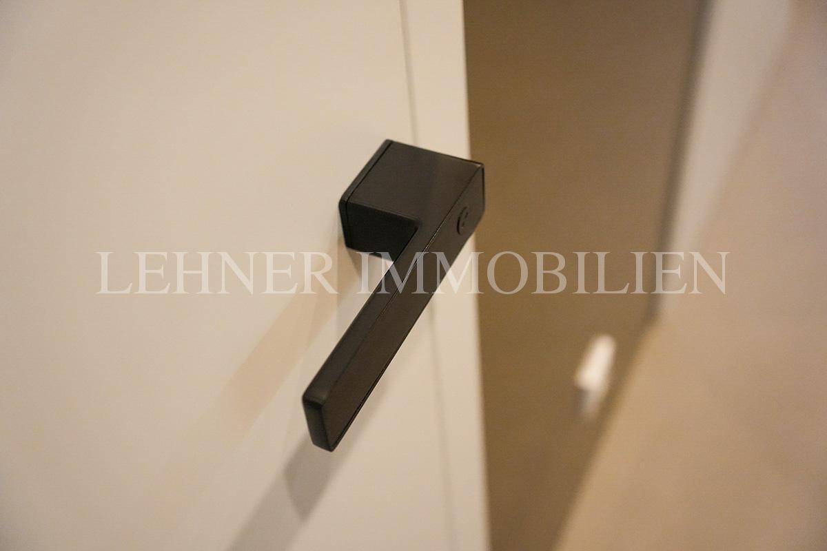 Moderne schwarze Türgriff-Detailaufnahme an einer weißen Tür.