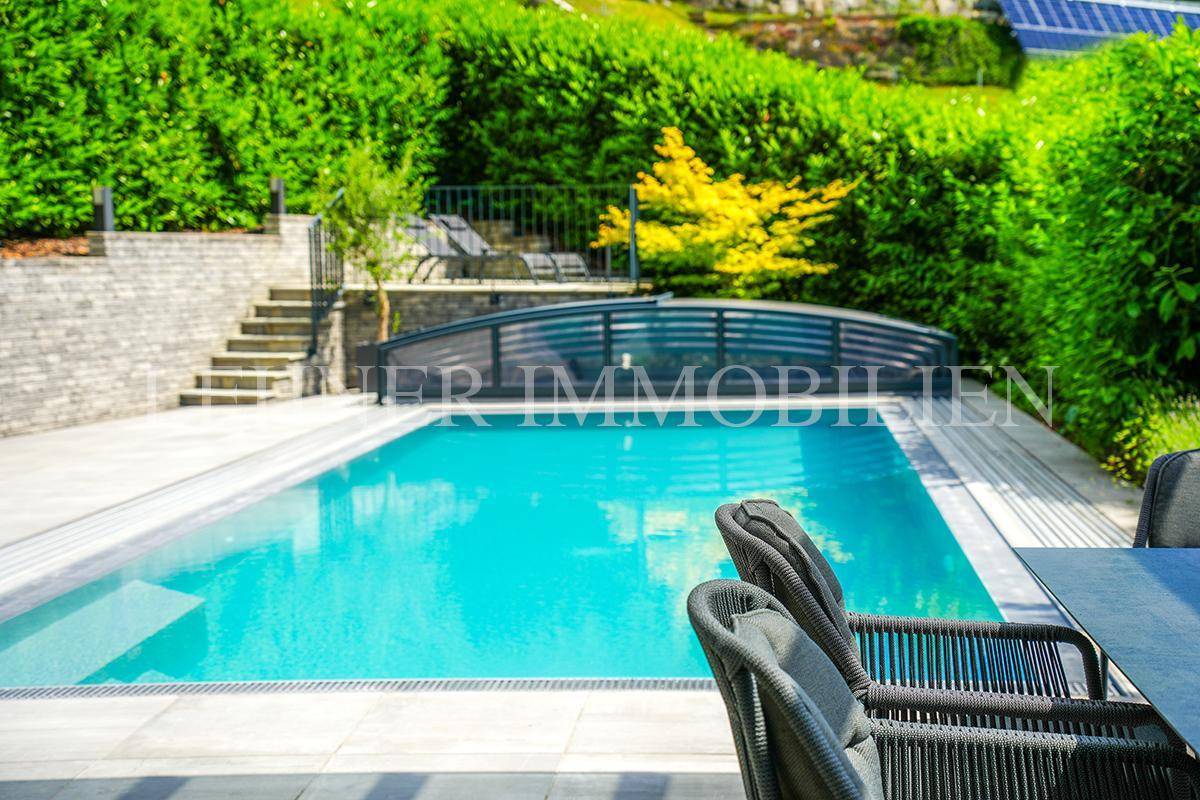 Erfrischender Swimmingpool mit Abdeckung, umgeben von gepflegter Gartenlandschaft.