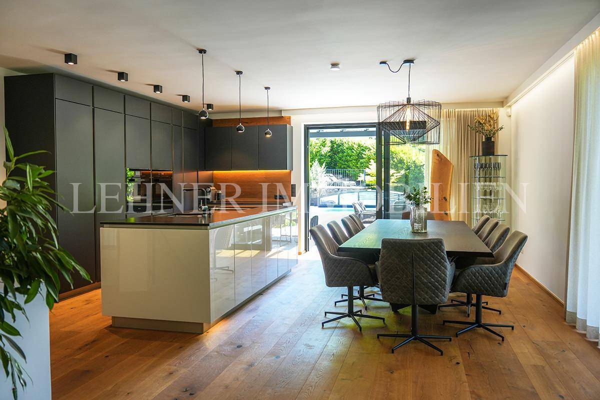 Moderne offene Küche mit Essbereich und Zugang zur Terrasse mit Poolblick.