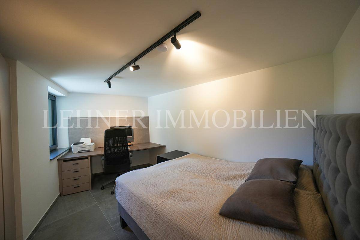 Komfortables Schlafzimmer mit großem Bett, Schreibtischbereich und Fenster.