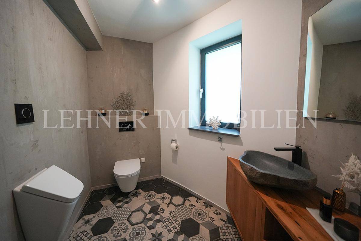 Modernes Gäste-WC mit auffälligen Fliesen, stilvollem Waschbecken und Fenster für Tageslicht.