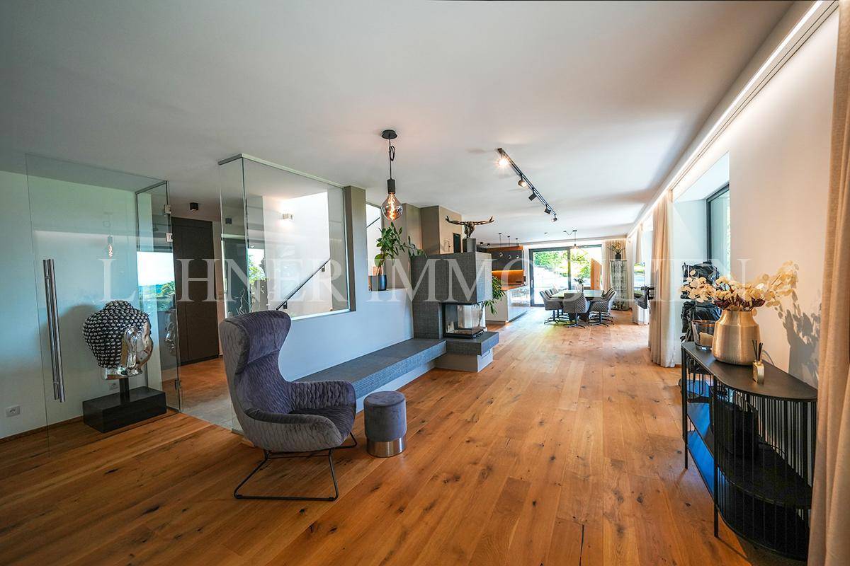 Offener Wohnbereich mit Holzboden, modernem Kamin und Treppe zum Obergeschoss.