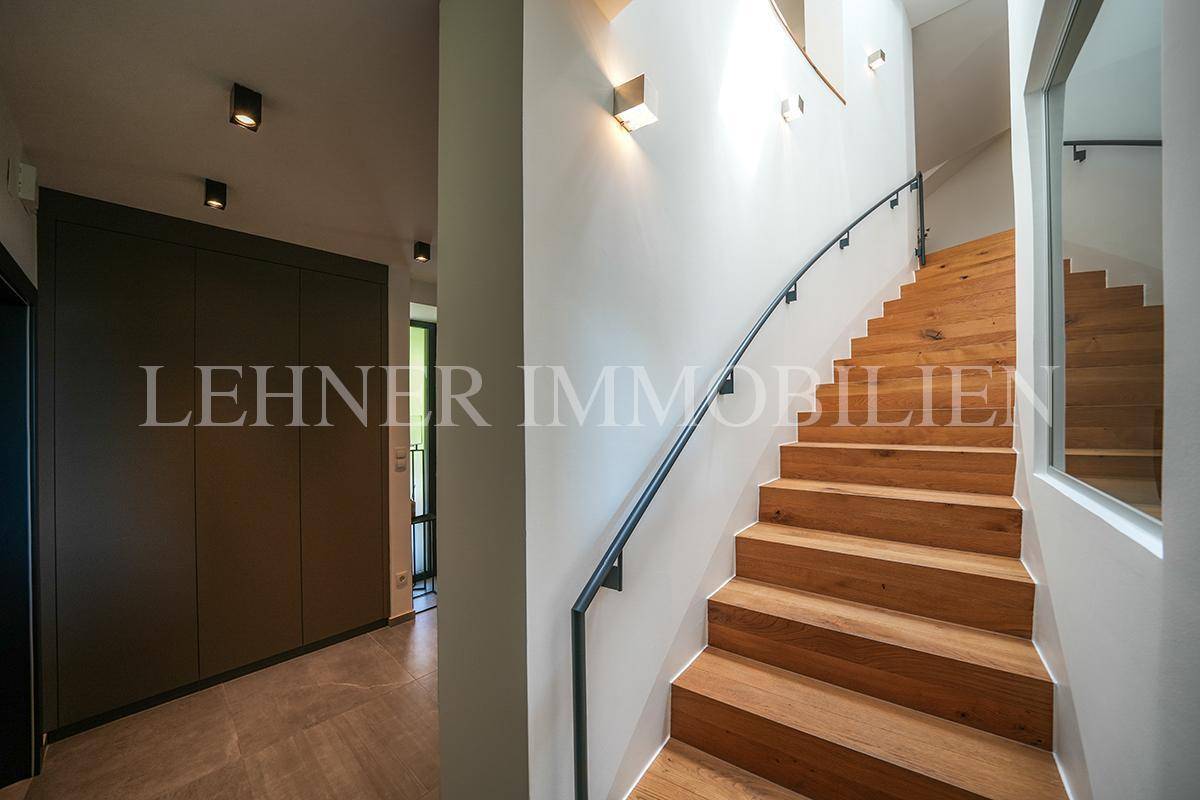 Elegante Holztreppe mit geschwungenem Geländer, die in die oberen Stockwerke führt.