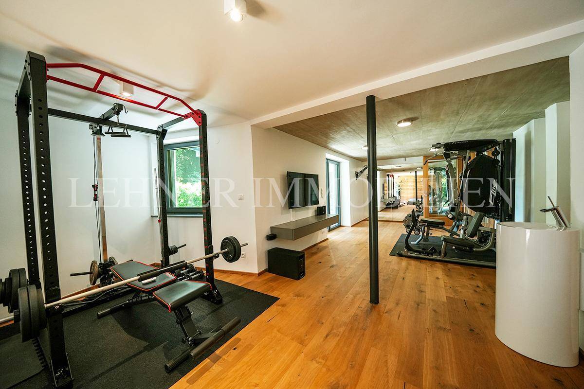 Gut ausgestatteter Fitnessraum mit Hantelbank, Power Rack und Holzboden.