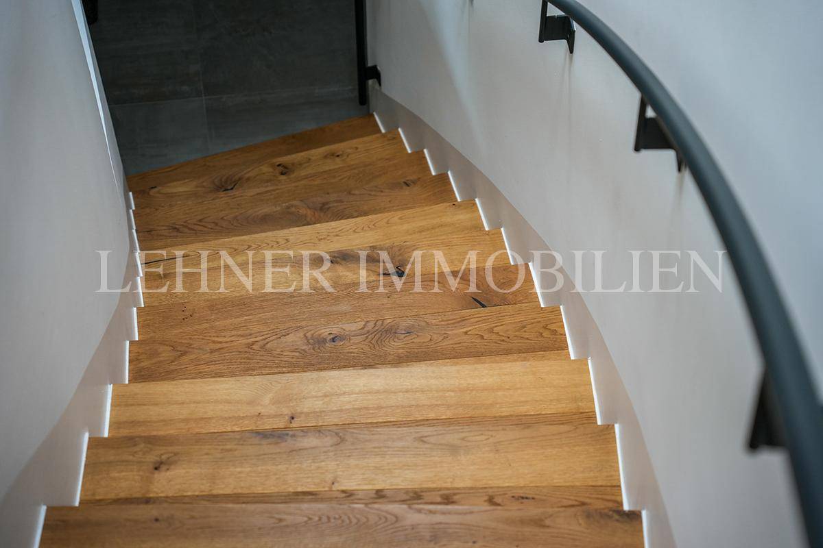 Elegante Holztreppe mit geschwungenem Design und schwarzem Metallgeländer.