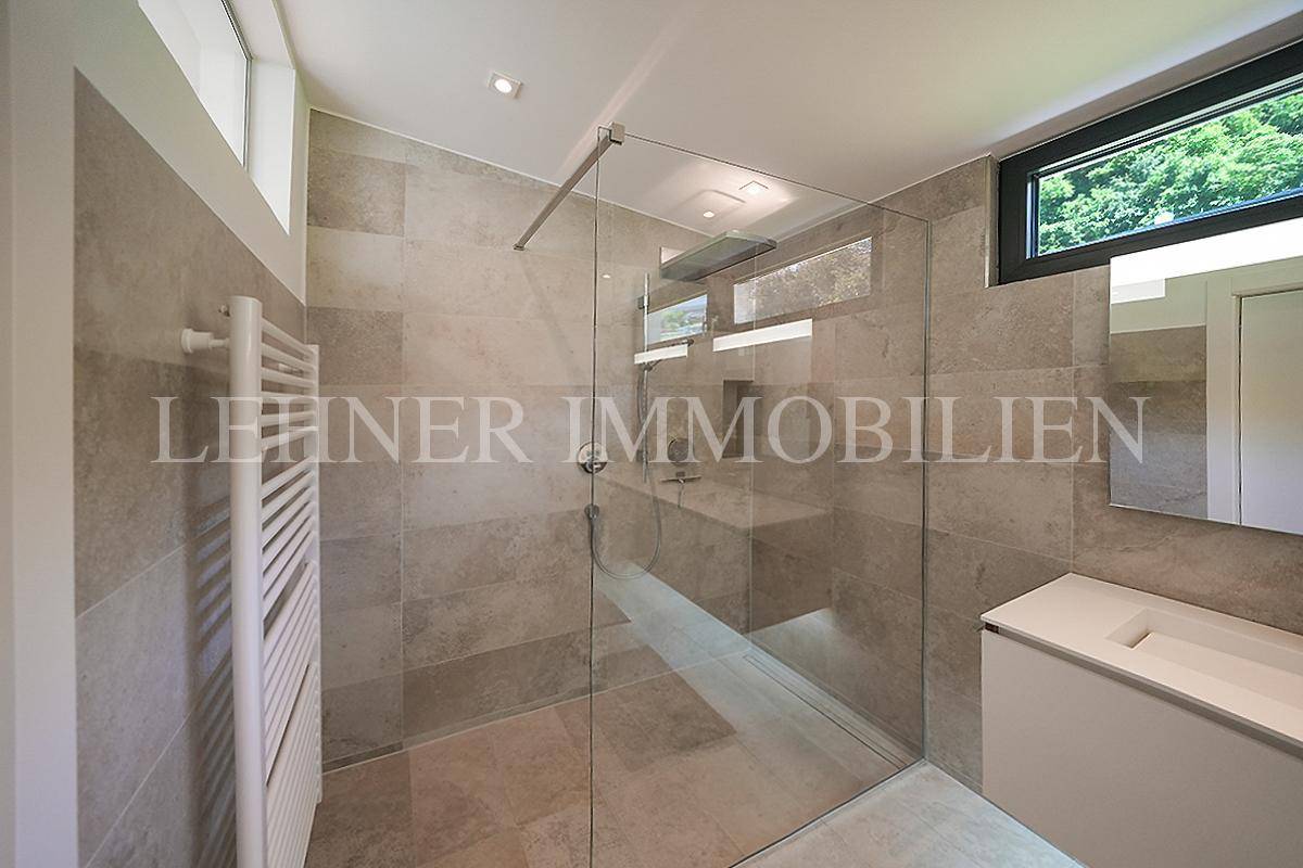 Elegante begehbare Dusche mit Glasabtrennung und modernen Fliesen im Badezimmer.