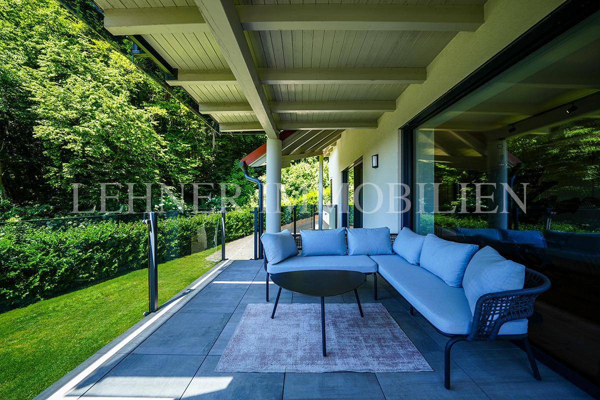 Überdachte Terrasse mit bequemen Outdoor-Sitzmöbeln und Blick ins Grüne.