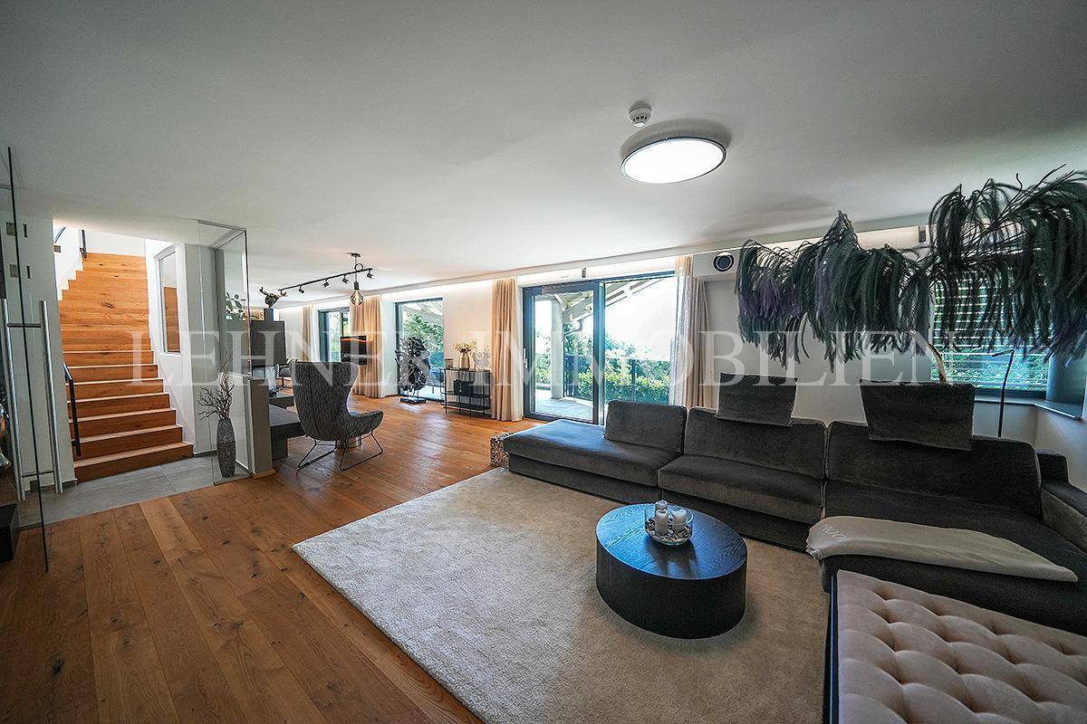 Helles Wohnzimmer mit großem Sofa, Holzboden und Zugang zur Terrasse.
