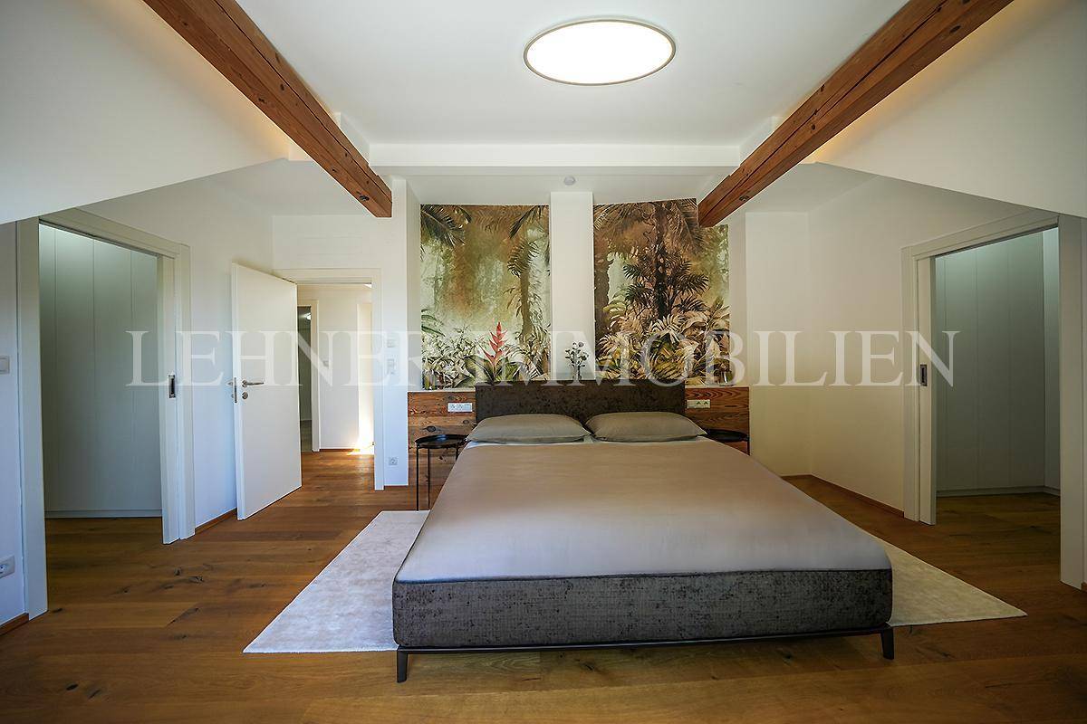 Gemütliches Schlafzimmer mit Holzboden, sichtbaren Holzbalken und dekorativer Wandgestaltung im tropischen Stil.