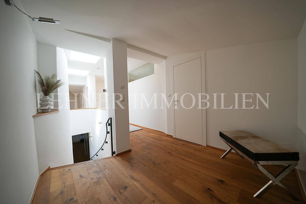 Heller Flur mit Holzfußboden, weiß gestrichenen Wänden und natürlichem Lichteinfall durch Oberlichter.