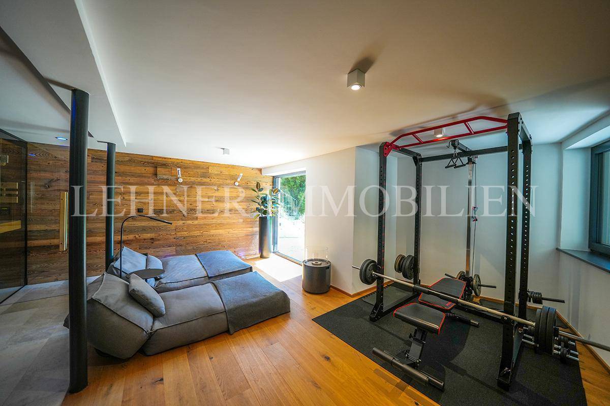 Fitnessbereich mit Kraftstation, bequemer Lounge und Holzwandverkleidung.